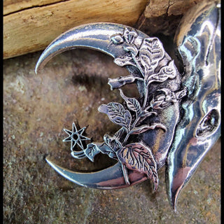 The left crescent moon of the barrette, intricately etched with floral details, including blooming flowers and vines. The design extends outward with a star motif, adding a celestial touch to the natural elements.