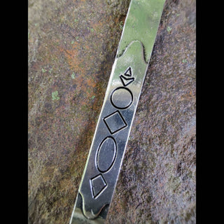 A close-up view of the Persephone hair dagger, focusing on the geometric engravings and crescent moon design along the blade. The polished silver surface captures light, accentuating the fine details and the dagger’s elegant, otherworldly aura.