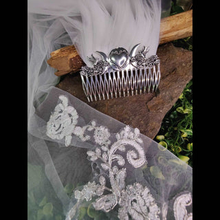 Bridal hair comb displayed on white lace veil. Natural backdrop and wooden elements. The setup enhances its bridal and ethereal appeal