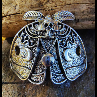 Close-up of the death moth hair cage, highlighting its textured metal wings, skull motif, and crescent moon detail