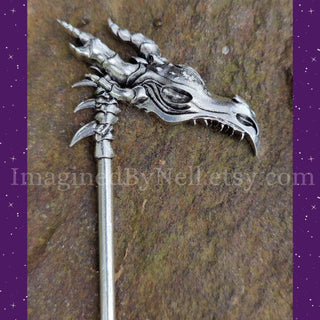 Detailed close-up of the silver dragon head hair scythe's intricate engraving and skeletal spine handle on a textured surface