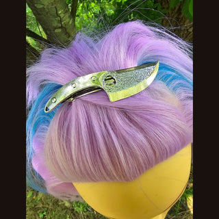  A close-up of a single knife hair clip nestled atop pastel pink hair with a hint of blue. The piece demonstrates its sharp, edgy aesthetic