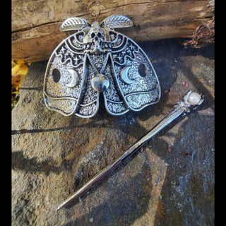 Death moth hair cage featuring intricate moon phases, skull detail, and a pearl-tipped hairpin, displayed on a rustic stone surface.