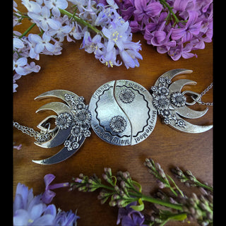 The best friend pendant set shown as a complete yin-yang pair, symbolizing connection and unity, with intricate floral accents and heartfelt engravings, framed with lilac flowers on a wooden table.