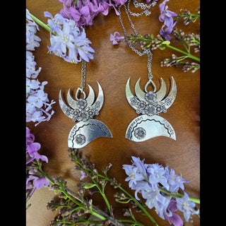 The matching best friend pendant set, forming a symbolic pair, displayed against a wooden surface with lilac blossoms, showcasing the meaningful engravings and floral designs